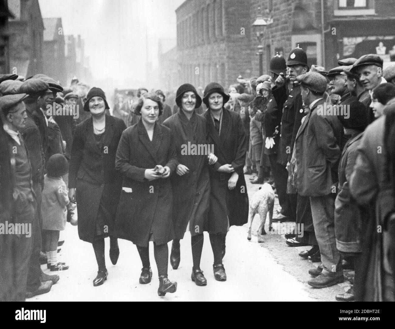 Un groupe de travailleuses a résisté à l'appel du syndicat et sont sur le point de travailler à Queens Mill à Burnley pendant la grève du textile. Ils sont flanqués par les travailleurs en textile frappants sur le côté de la route. Banque D'Images