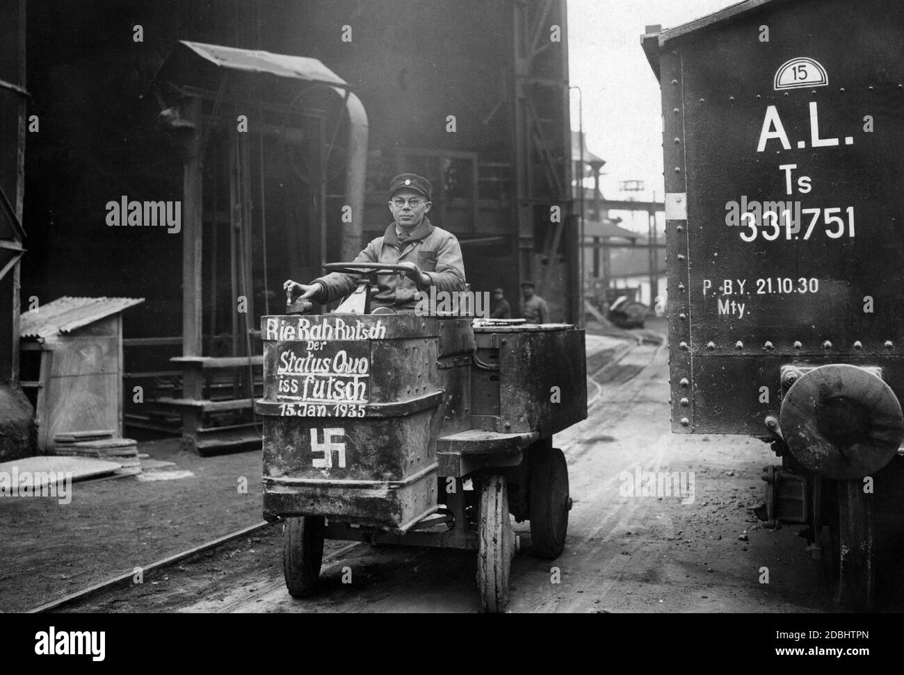 "Dans les locaux d'une société en Sarre, un ouvrier conduit une voiture avec une croix gammée et l'inscription: ''Rie Rah Rutsch Der Statut quo iss futsch 15. Jan 1935'' (Anglais: RI-ra-roach! Le statu quo a disparu, le 15 janvier 1935). Banque D'Images