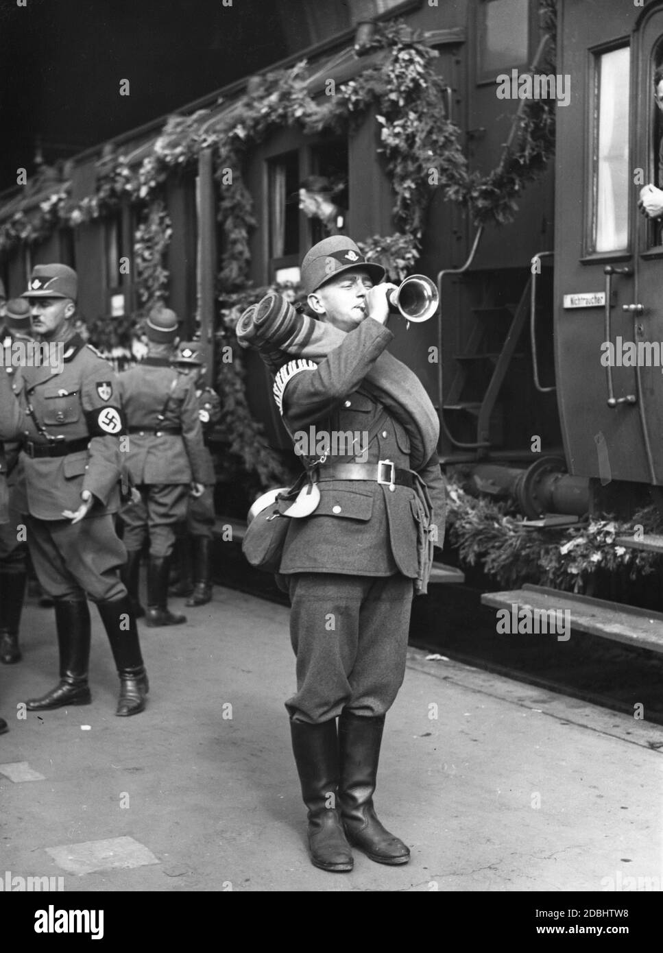 Un membre du Service national socialiste du travail utilise une trompette pour donner le signal de monter à bord du train spécial décoré quittant Berlin à 15 heures pour le Congrès du Parti nazi à Nuremberg, sur lequel se déplace le Gau 9 du Service du travail. Banque D'Images