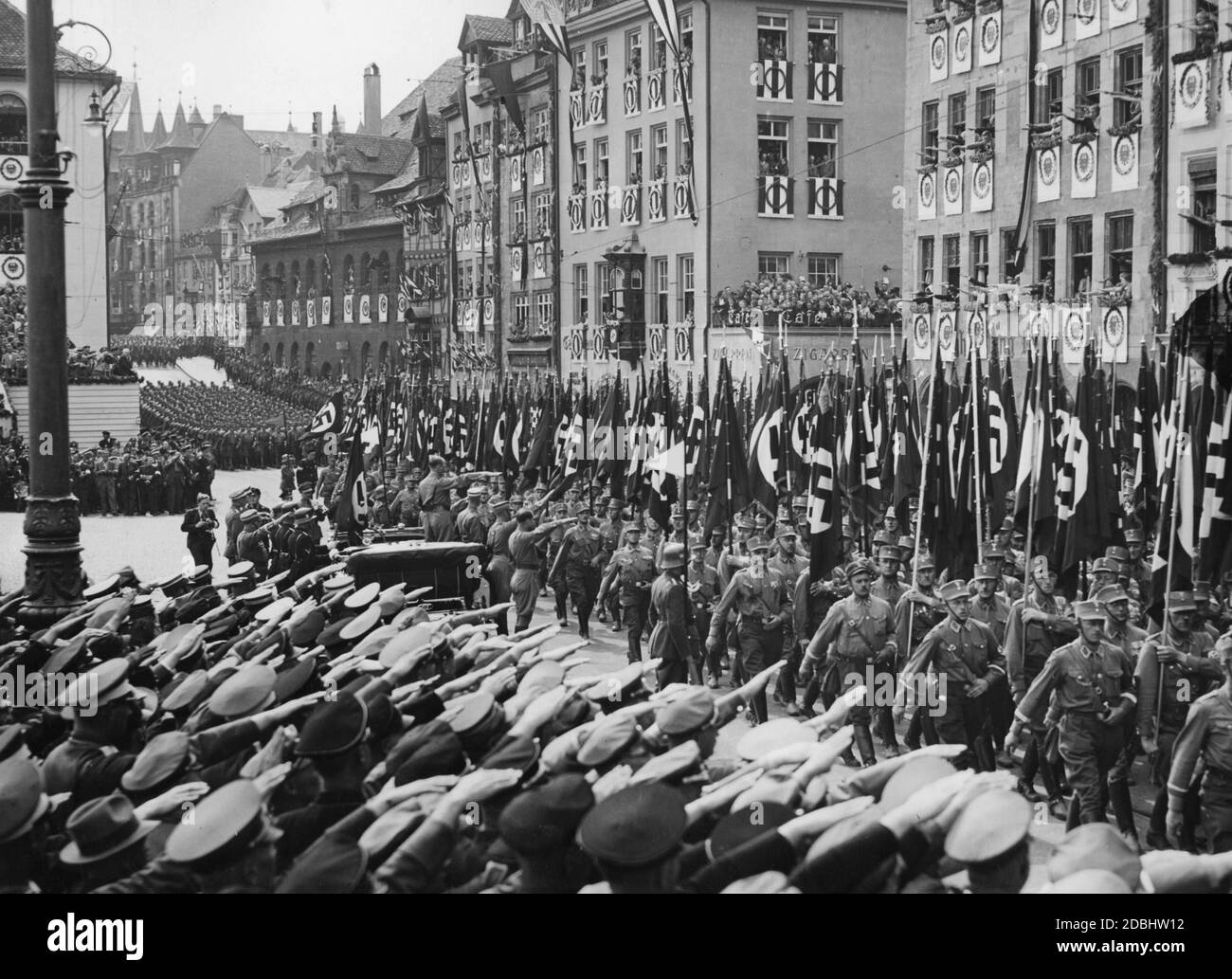 Adolf Hitler (debout dans sa Mercedes) prend le salut des formations de la sa et des organisations politiques sur la place du marché principal de Nuremberg. En face de lui sont Viktor Lutze et Rudolf Hess. Heinrich Hoffmann avec un appareil photo est laissé derrière eux. Banque D'Images