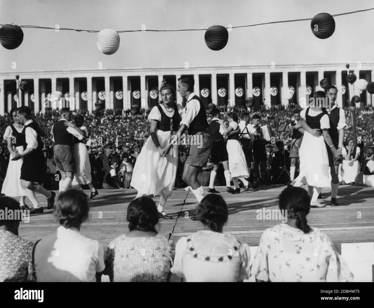 Un groupe de danse folklorique en danses traditionnelles sur un podium lors du festival folklorique sur le terrain de Zeppelin. En arrière-plan le stand de Zeppelin. Banque D'Images