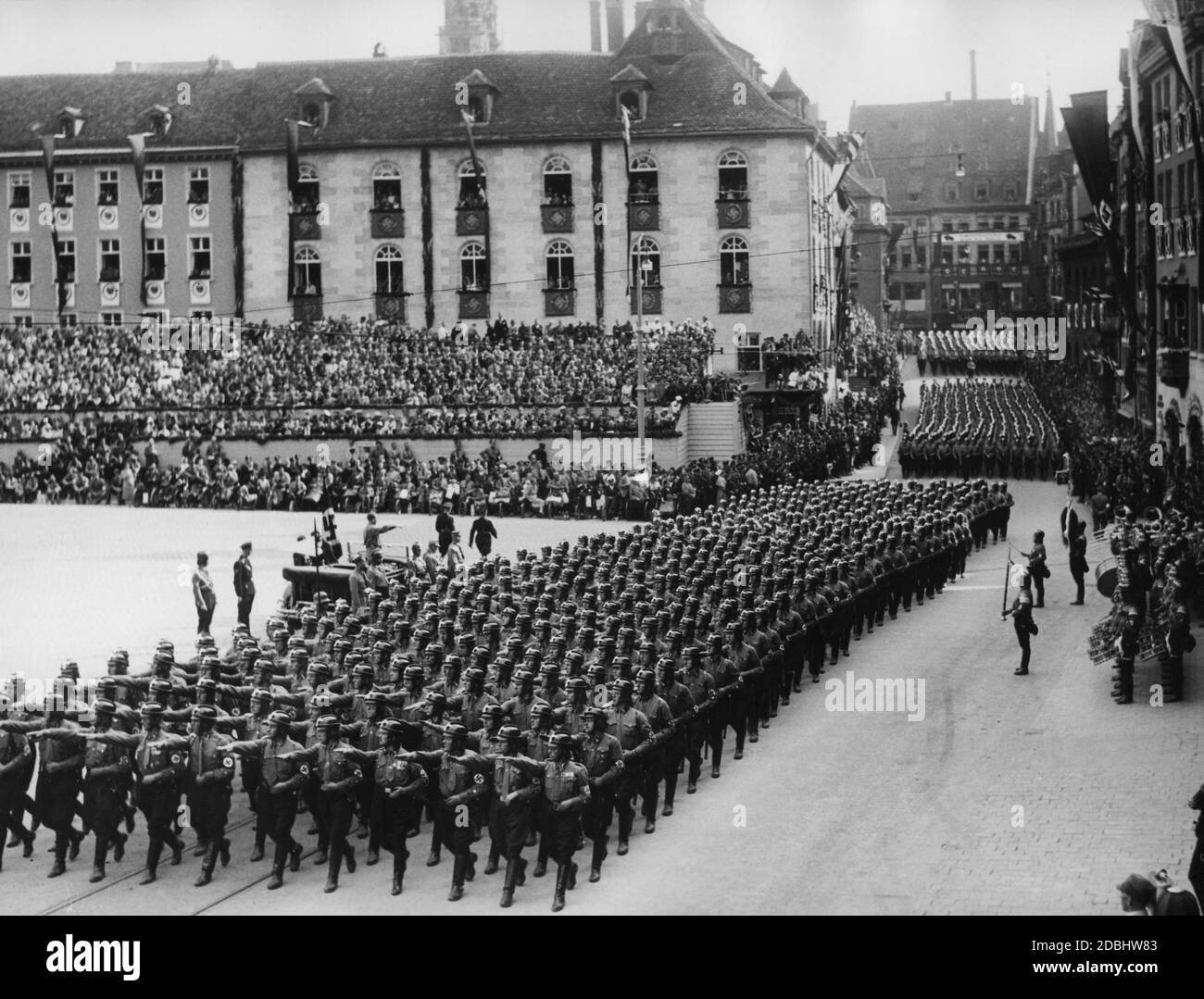 Situé dans une automobile sur la place du marché principal de Nuremberg, Adolf Hitler salue le NSKK lors du Congrès du Parti nazi à Nuremberg. Sur la droite, se trouve un groupe de cuivres et des batteurs. Banque D'Images