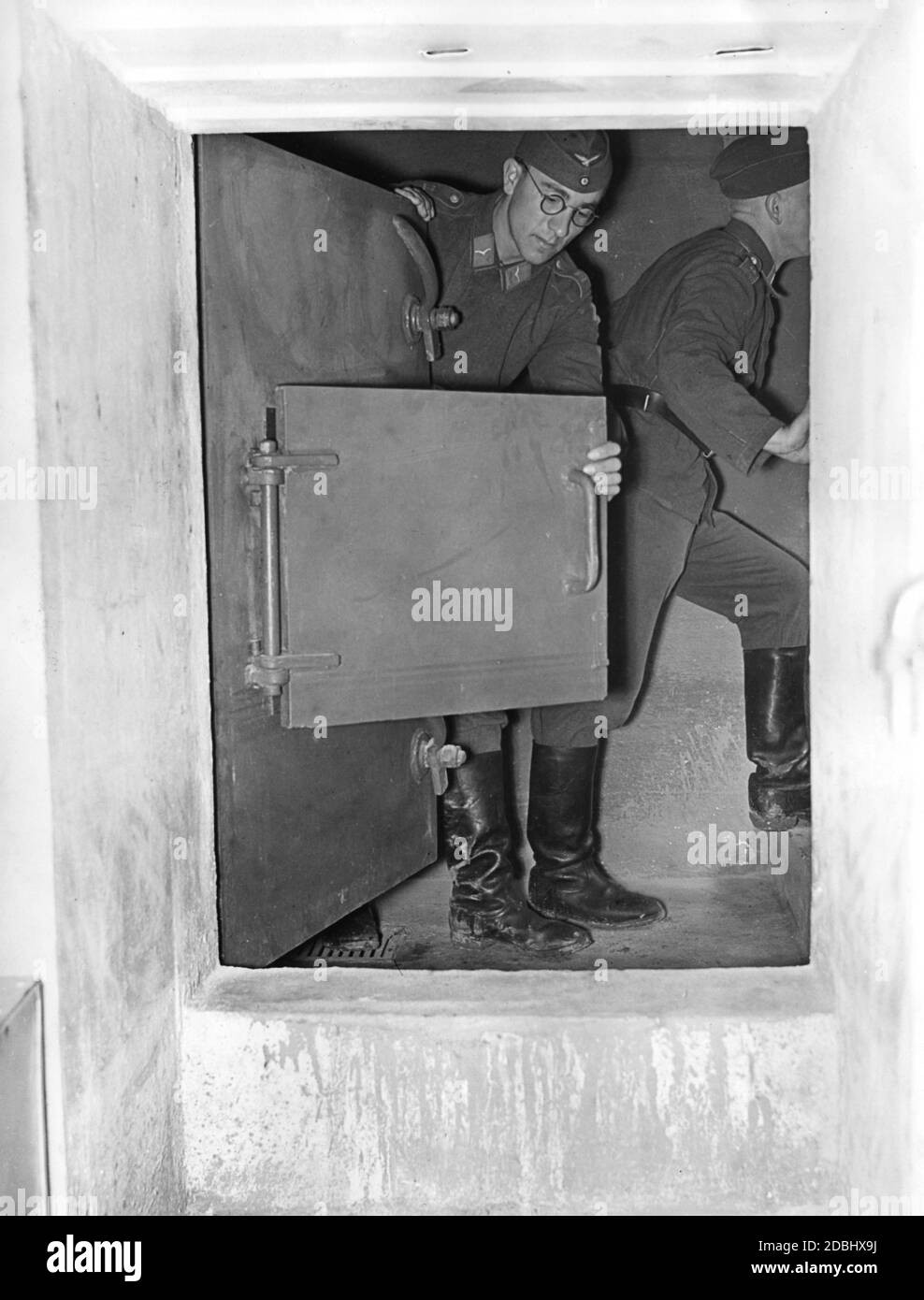 « un soldat montre le mécanisme de fermeture de la porte d'entrée d'un bunker de Fuehrer lors d'une tournée de presse dans la zone de défense aérienne Ouest en août 1939. Les rapports sur la ''Westwall'' (ligne Siegfried) avaient pour but de soulager la crainte de la population d'une guerre imminente sur deux fronts.' Banque D'Images