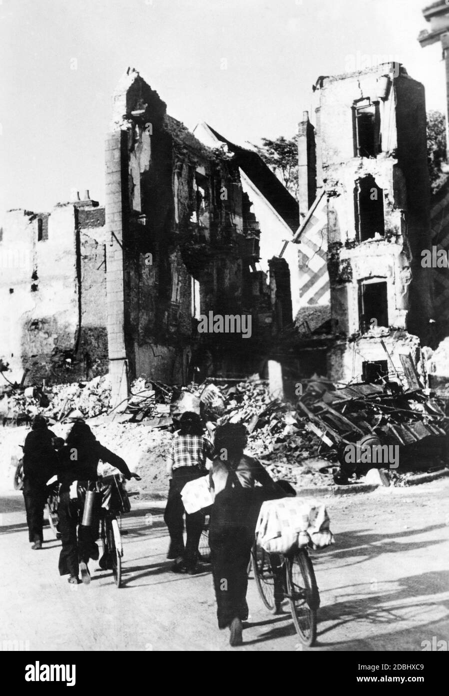 Des civils marchent avec leurs bagages parmi les ruines de la ville française détruite de Courtenay dans le Pay de la Loire. Banque D'Images