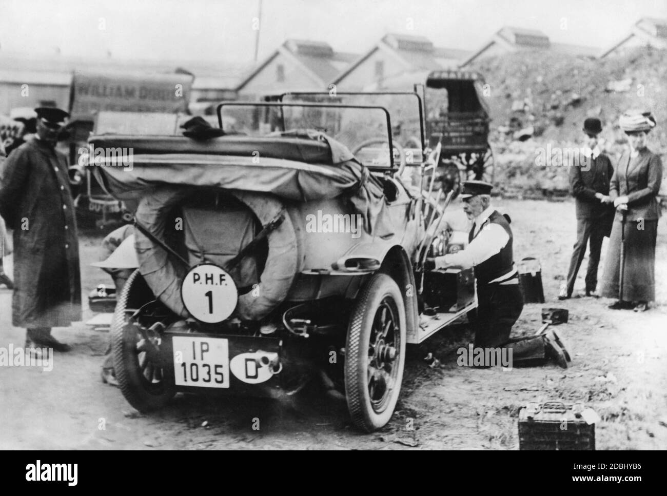 Sur cette photo de 1911, le prince Henry de Prusse (à droite, à genoux) répare la voiture avec laquelle il a participé à la dernière Prinz-Heinrich-Fahrt. La voiture portant le numéro 1 est un modèle de production de la marque Benz (Benz 8 avec 18 hp) avec l'identifiant IP de la province de Schleswig-Holstein. Banque D'Images