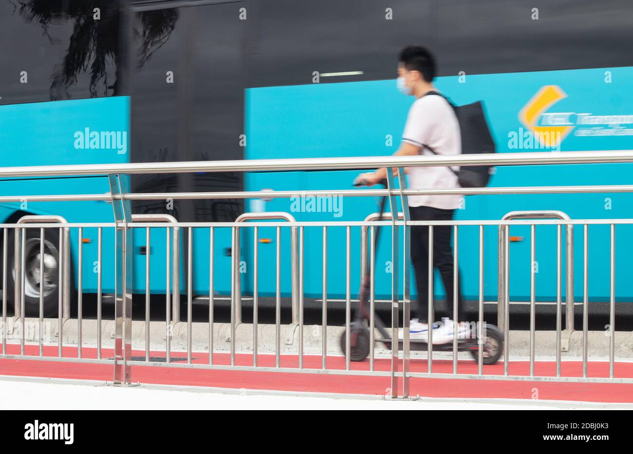 Homme portant un revêtement de visage de scooter électrique sur la piste cyclable près de passer le bus en Espagne. Banque D'Images