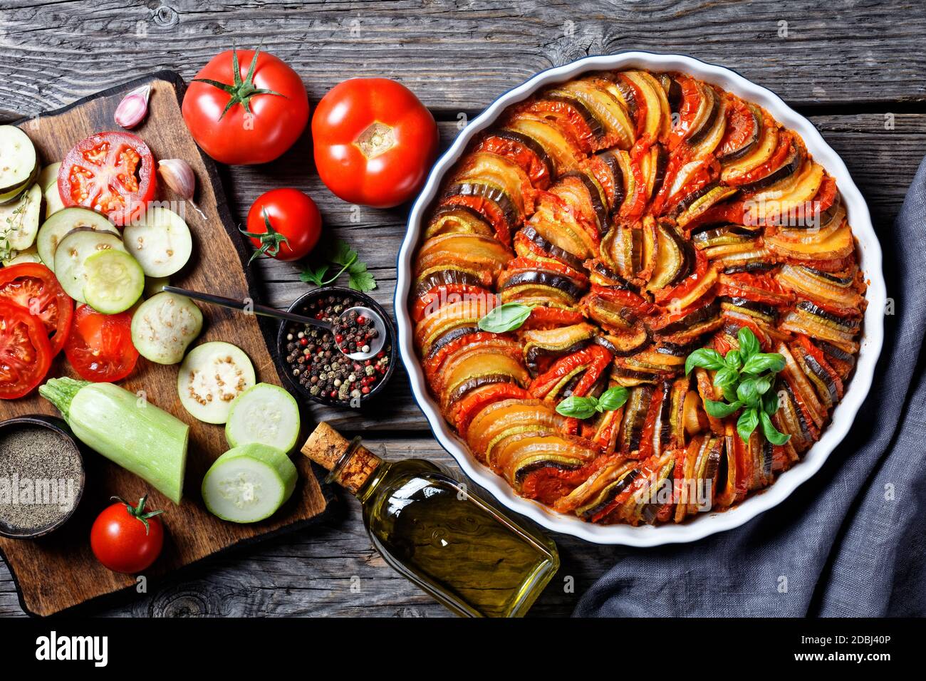 ratatouille, ragoût de légumes en tranches d'aubergines, courgettes, oignons et pommes de terre avec sauce tomate, ingrédients à l'arrière-plan, cuisine française, horizonta Banque D'Images