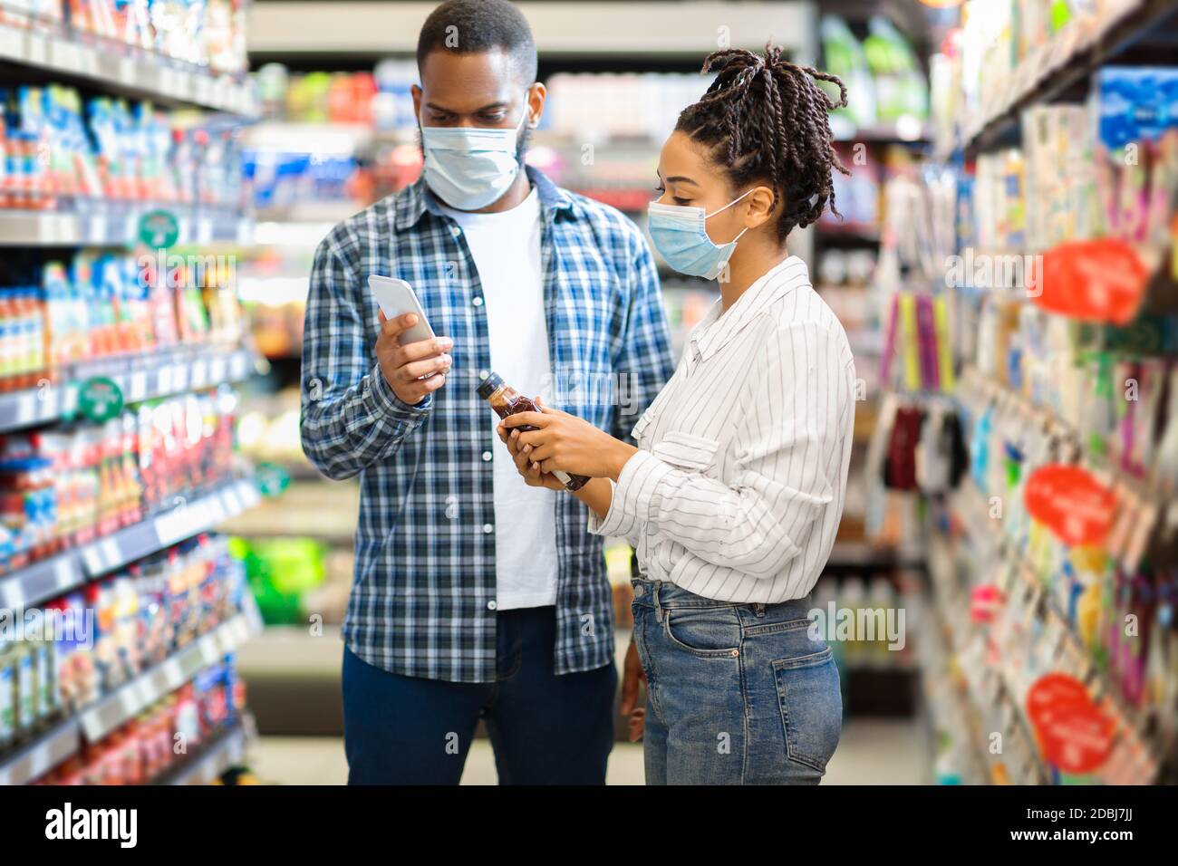 Couple africain utilisant le téléphone intelligent scannant les produits alimentaires dans le supermarché Banque D'Images