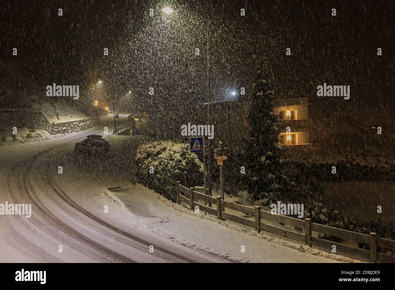Chute de neige la nuit à Selva Gardena avec lumière de rue et marques de pneus ao sur la neige fraîche, Dolomites, Italie Banque D'Images