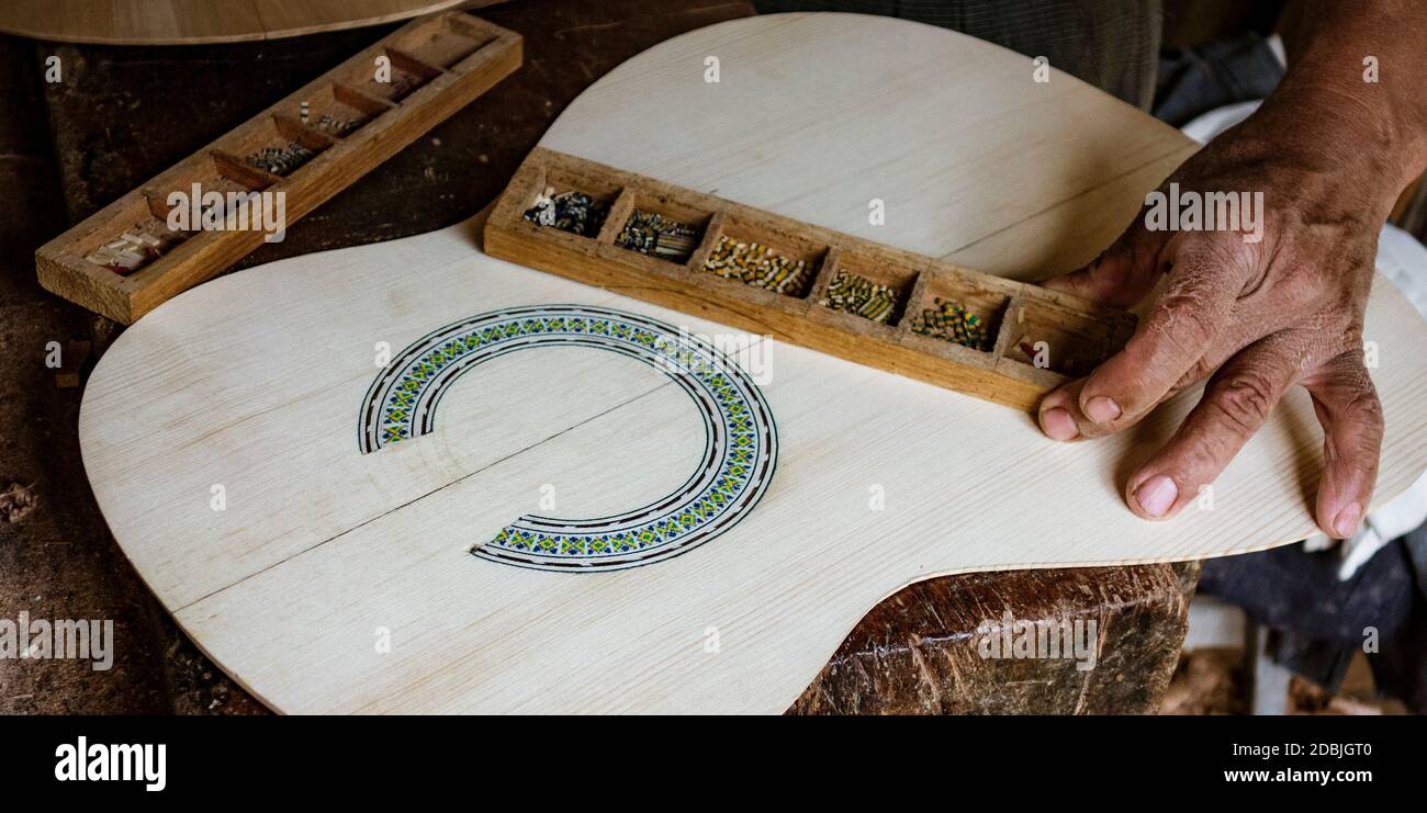 Homme met la touche finale à l'inlay autour d'une rosace dans un nouvel instrument Banque D'Images