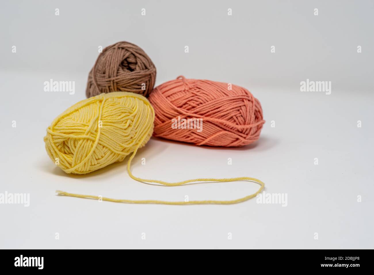 Trois balles de fil de laine coloré sur un fond blanc Uni avec espace de copie. Banque D'Images