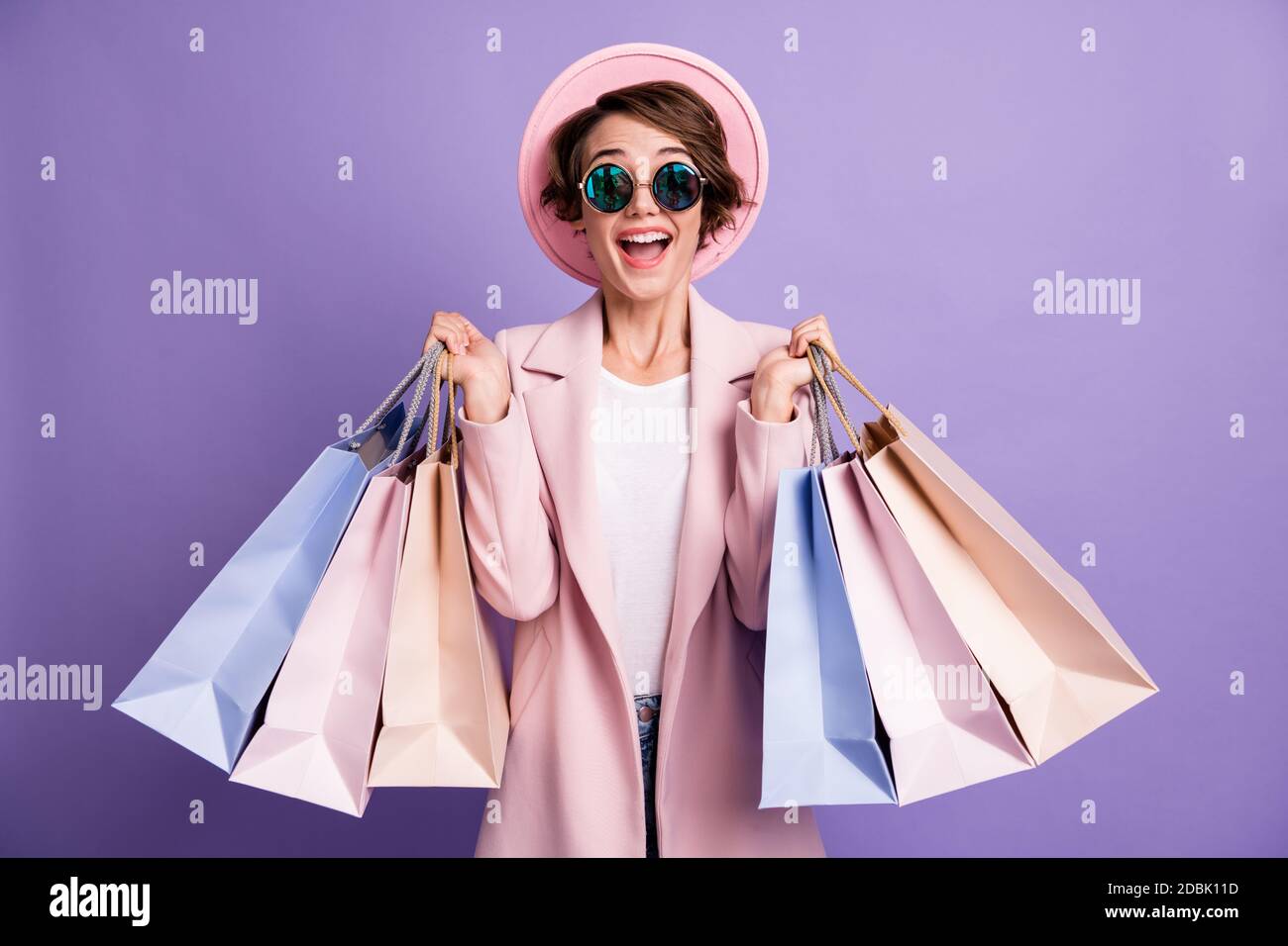 Portrait de la fille excitée joli positif tenir les sacs d'atelier ne  shopping vêtements lunettes rose chapeau manteau isolé sur la couleur  pourpre arrière-plan Photo Stock - Alamy