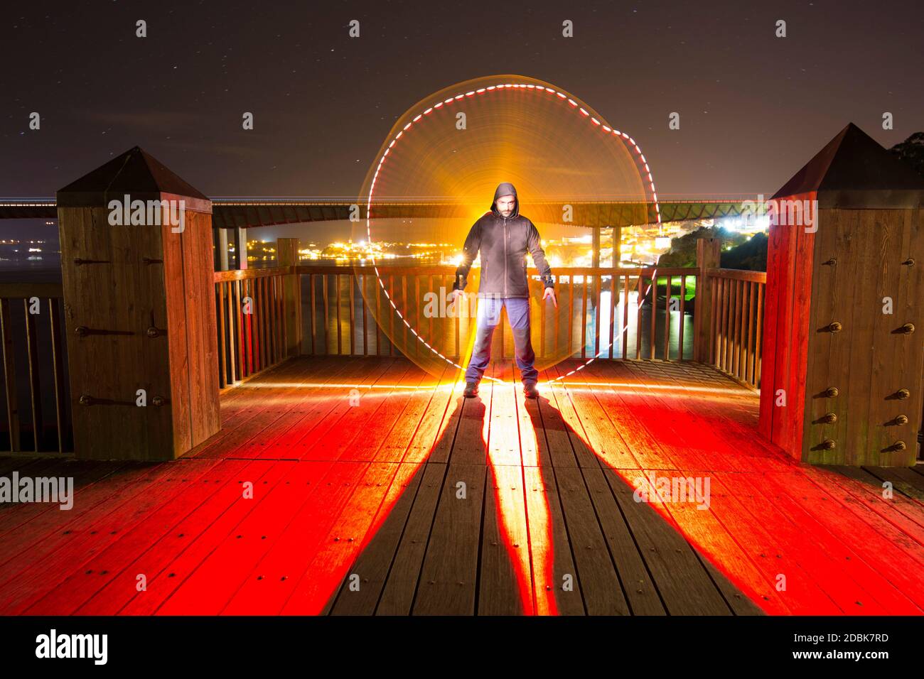 Homme illuminé de techniques de peinture lumineuse avec lumière artificielle sur le pont d'une falaise. Banque D'Images