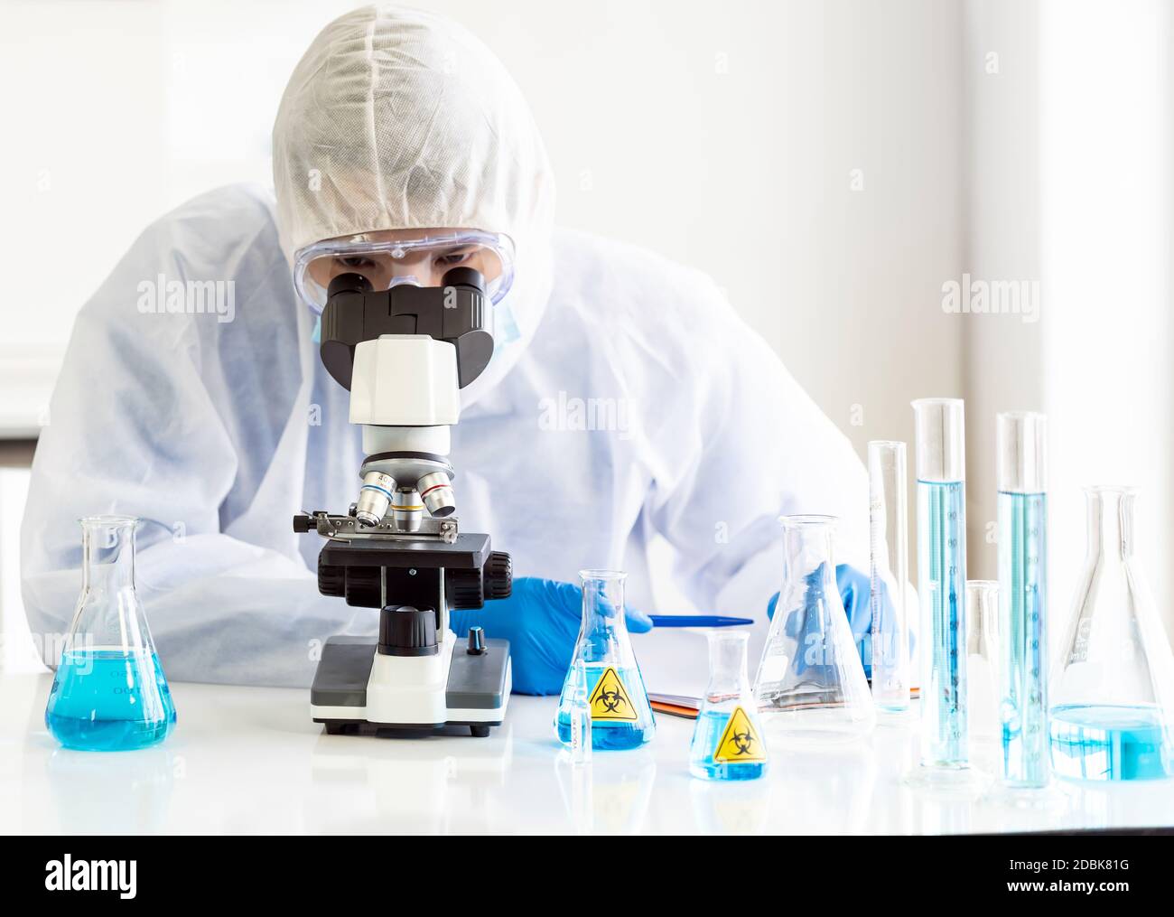 Jeunes scientifiques asiatiques faisant des recherches et regardant à travers un microscope dans un laboratoire pour étudier sur le coronavirus COVID-19 pour développer le vaccin FO Banque D'Images