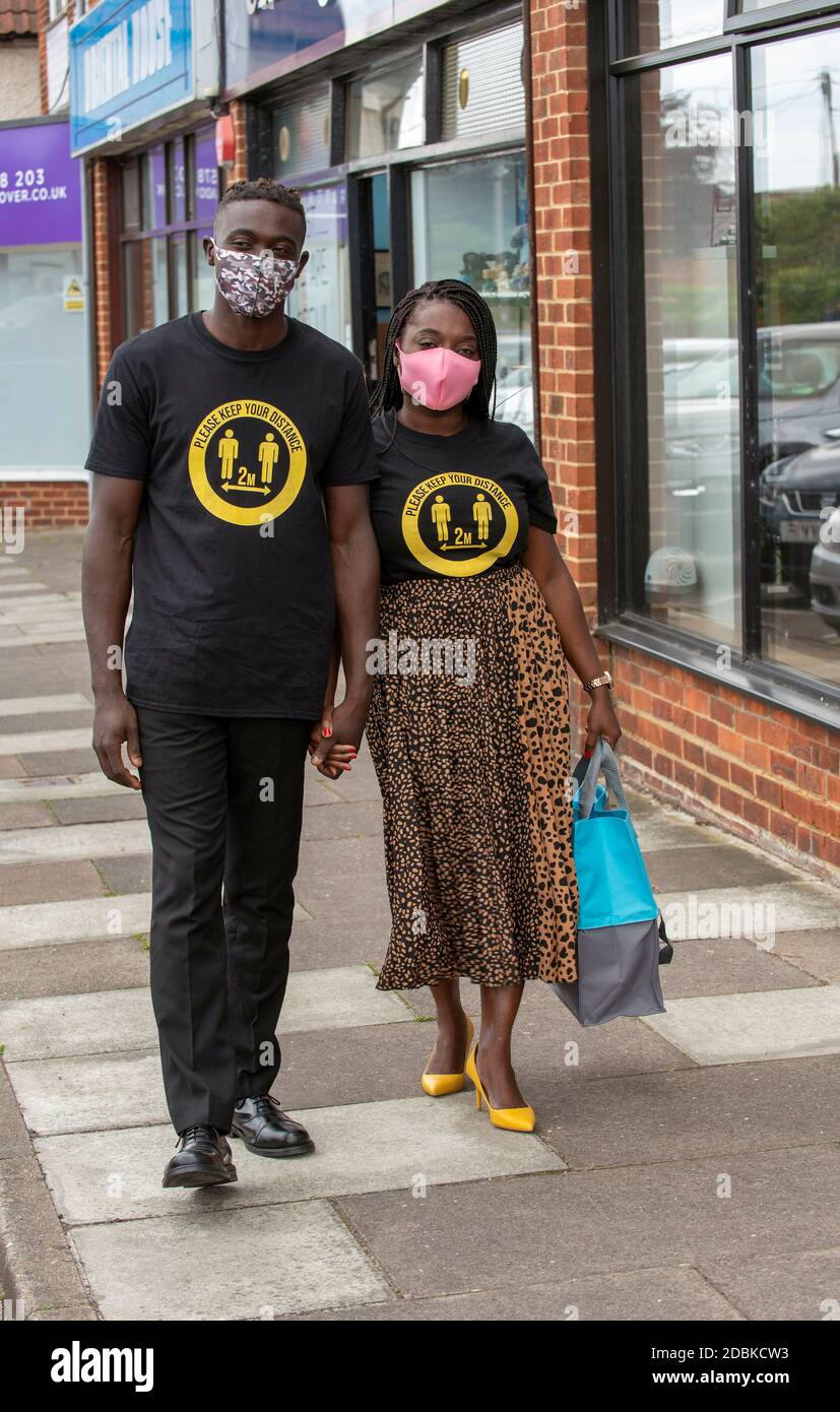 Hampshire, Angleterre, Royaume-Uni. 2020, Black couple portant garder vos chemises de distance pendant l'épidémie de covid dehors aux magasins. Banque D'Images