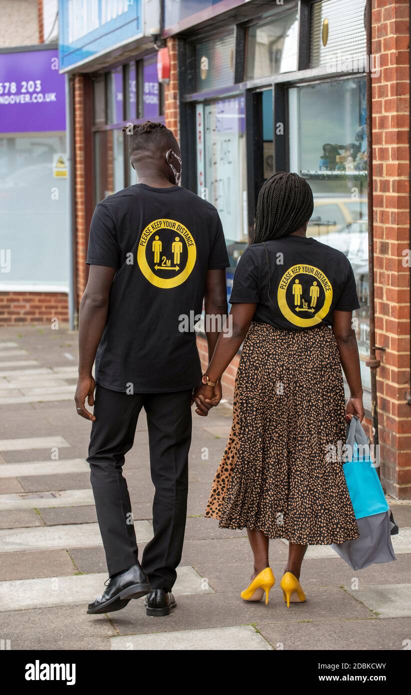 Hampshire, Angleterre, Royaume-Uni. 2020, Black couple portant garder vos chemises de distance pendant l'épidémie de covid dehors aux magasins. Banque D'Images