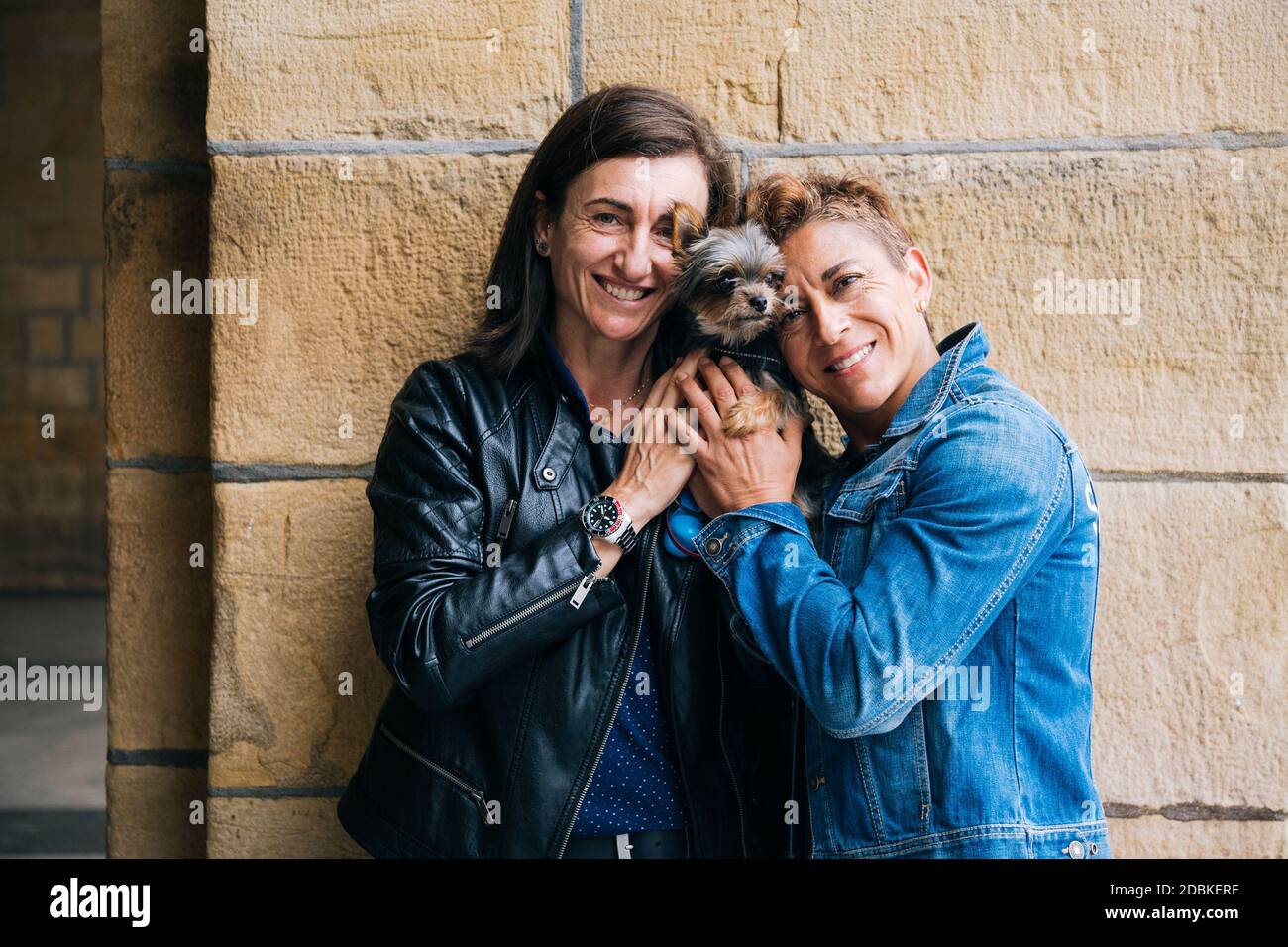 Portrait d'un heureux couple lesbien d'âge moyen embrassant leur terrier du yorkshire Banque D'Images