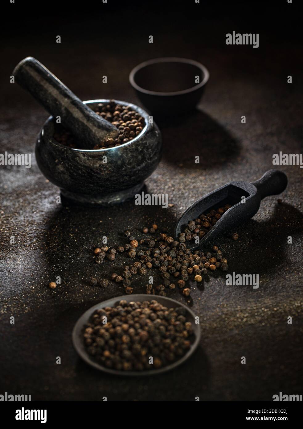 Concept de grains de poivre noir biologique brut sur fond sombre Banque D'Images