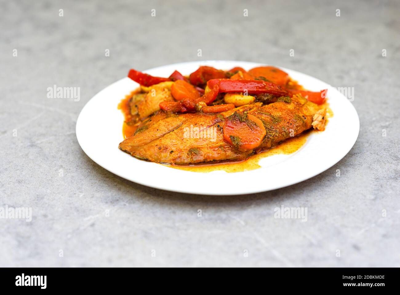 Chraime sur une table en marbre. Chraime - poisson-chauve-souris mijoté dans une sauce tomate chaude, ail, poivre, citron et épices. Traditionnel libyen, marocain, juif, sépharade, plat arabe. Banque D'Images