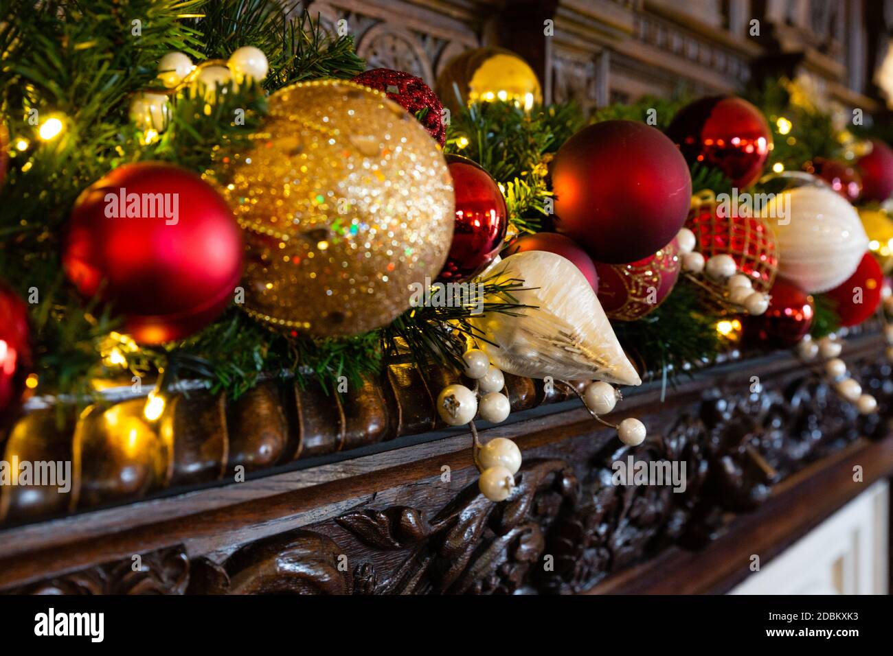 Un beau feu de bois traditionnel entouré de sculptures complexes ornées d'une guirlande de Noël festive de rouge, de vert et d'or. Banque D'Images