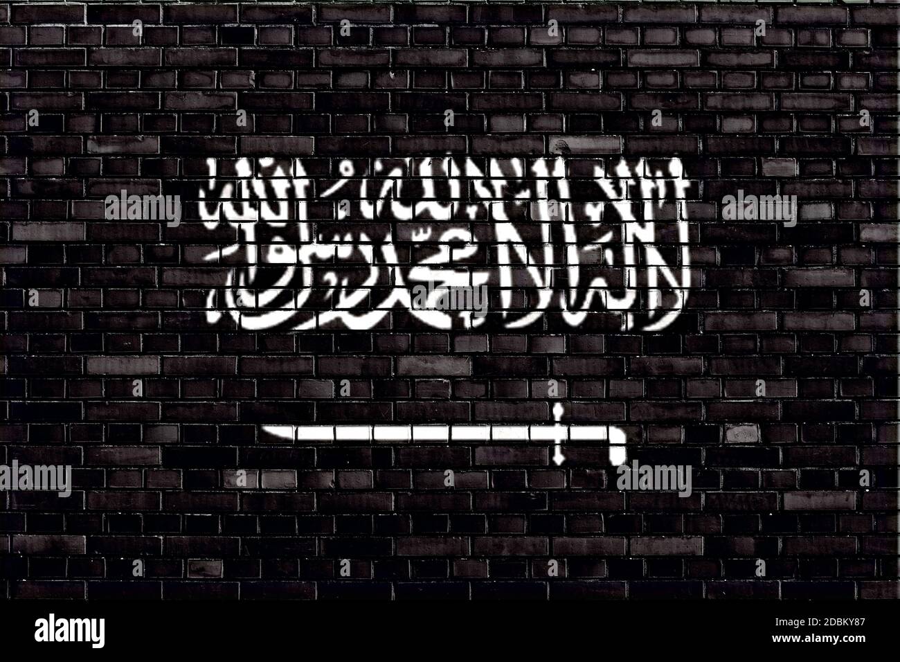 Drapeau noir du Jihad peint sur mur de brique Banque D'Images