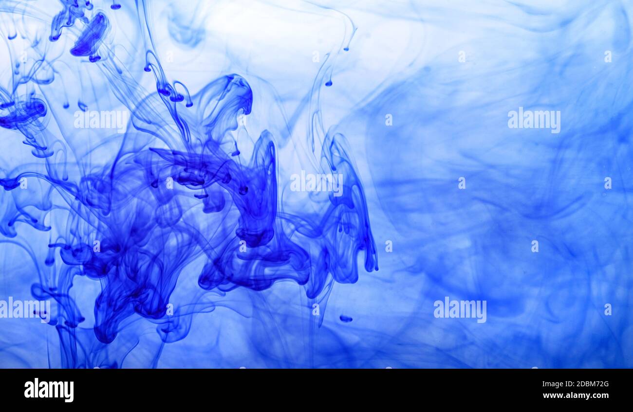 Encre bleue injectée dans l'eau à partir de la seringue, mélange de couleur avec de l'eau créant des formes abstraites. Banque D'Images
