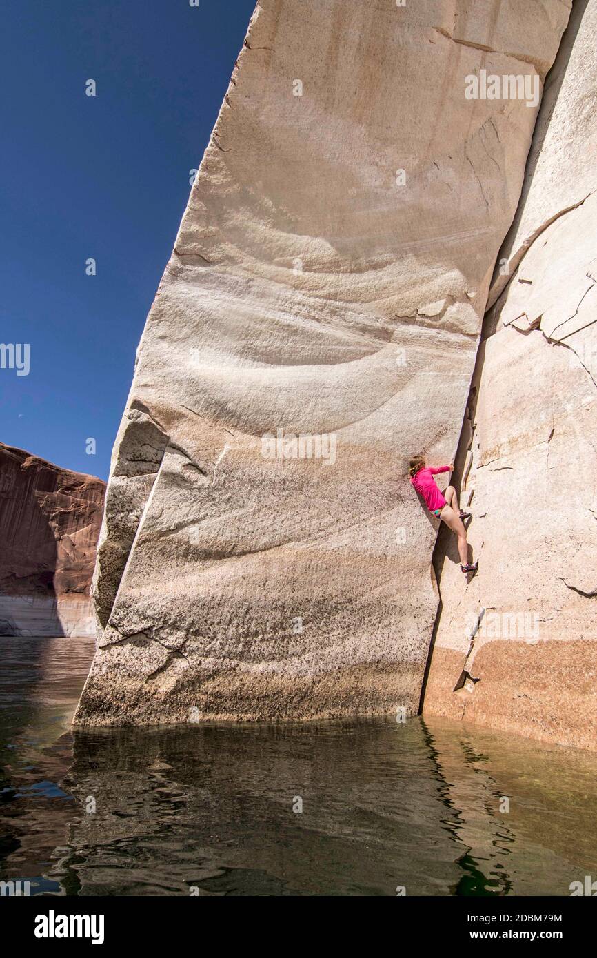 Une jeune femme craque monte sans corde au-dessus de la Eaux calmes du lac Powell Banque D'Images