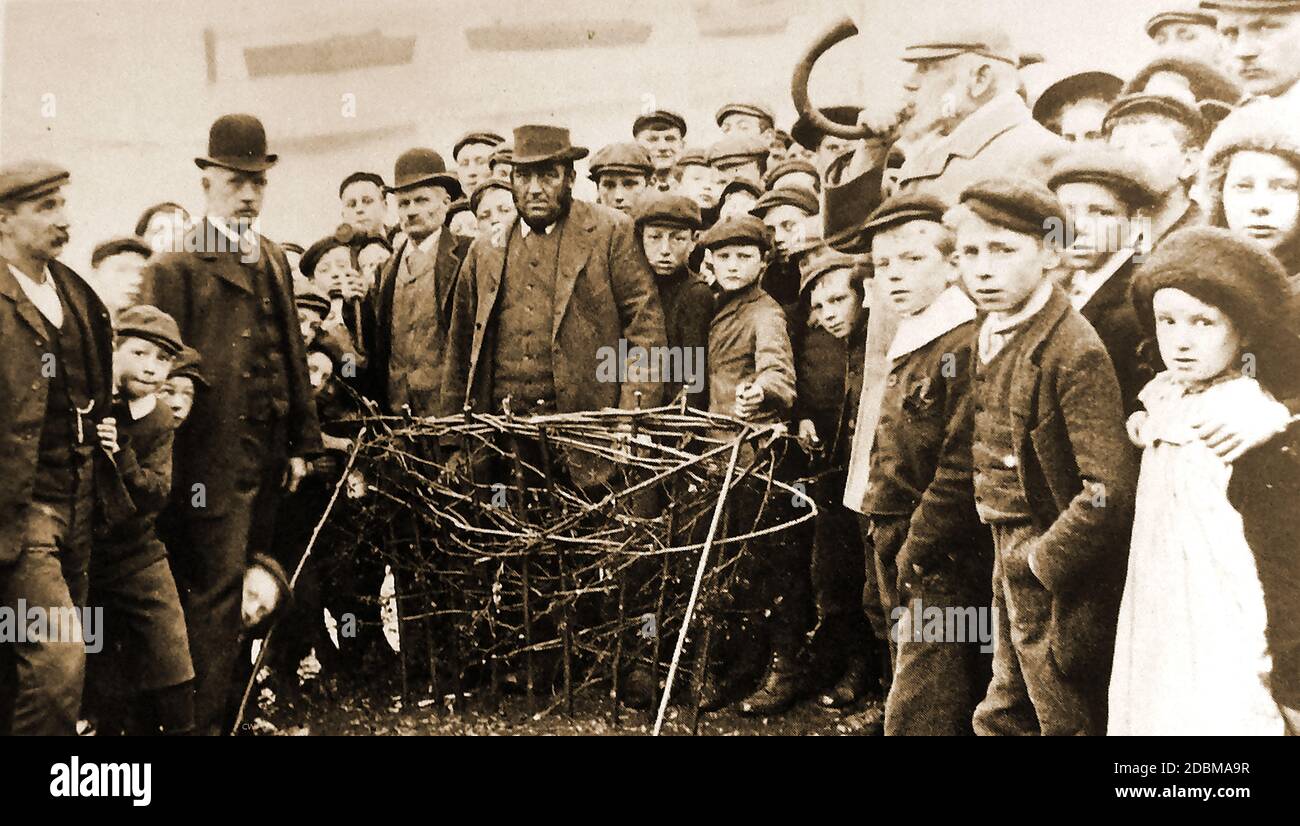 Whitby (Yorkshire UK,) cérémonie traditionnelle de haies Horngarth ou Penny 1906. Une photographie historique montrant la cérémonie annuelle de plantation de la haie de Penny ou Horngarth dans la rivière Esk à Whitby, dans le North Yorkshire, au Royaume-Uni, en 1911. À la fin de la haie, l'homme avec la corne souffle sur vous (sortez) en défiant la marée de détruire la haie de penny dans trois marées, en ligne avec une légende locale. La coutume a lieu au sein du sein d'Abraham la veille de l'Ascension (40e jour après le dimanche de Pâques) , dans la boue de la rive est de l'Esk . Banque D'Images