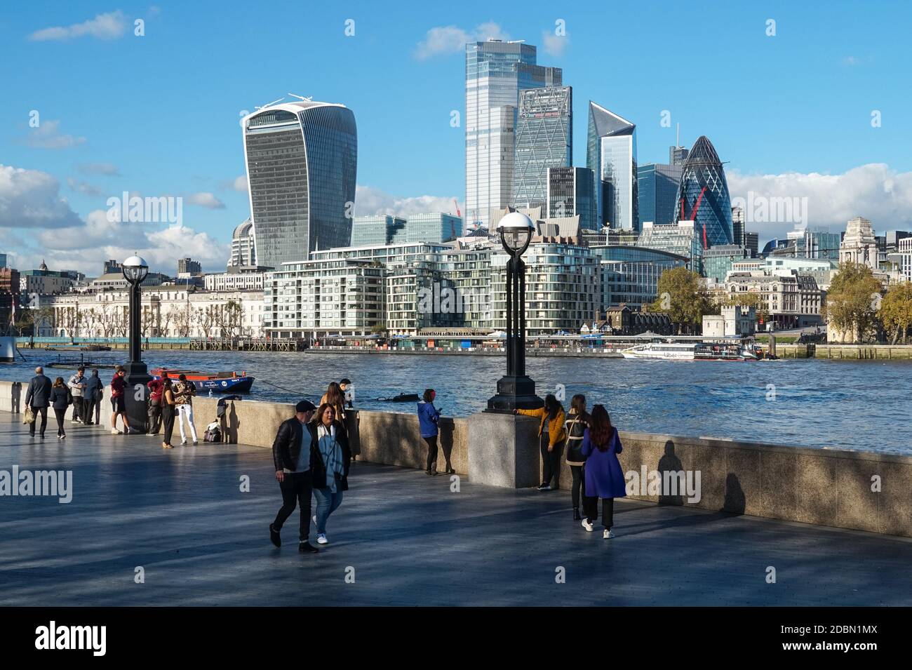 Les gens qui apprécient la journée ensoleillée à southbank of River Thames avec les gratte-ciels de la ville en arrière-plan, Londres Angleterre Royaume-Uni Banque D'Images