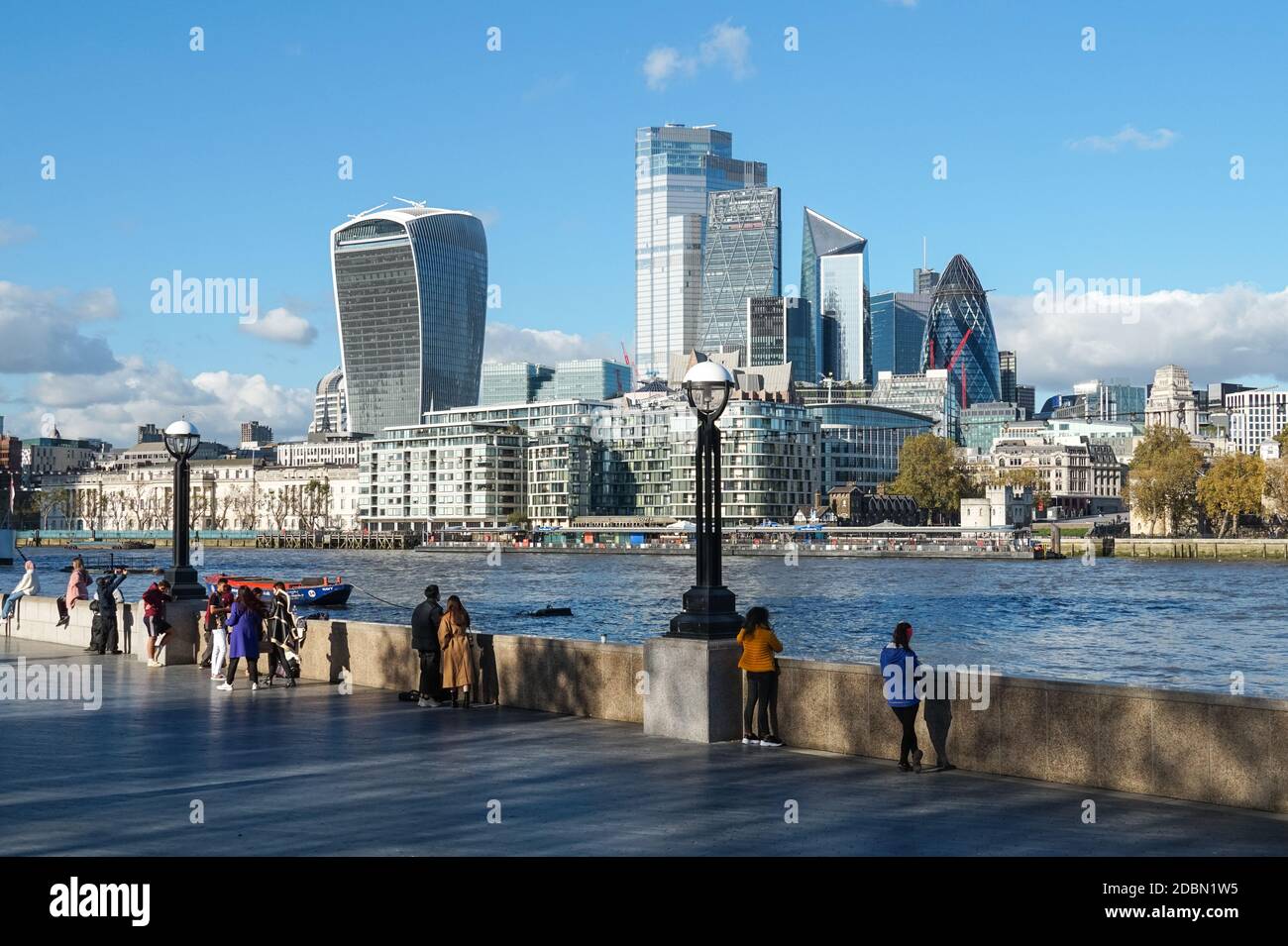 Les gens qui apprécient la journée ensoleillée à southbank of River Thames avec les gratte-ciels de la ville en arrière-plan, Londres Angleterre Royaume-Uni Banque D'Images
