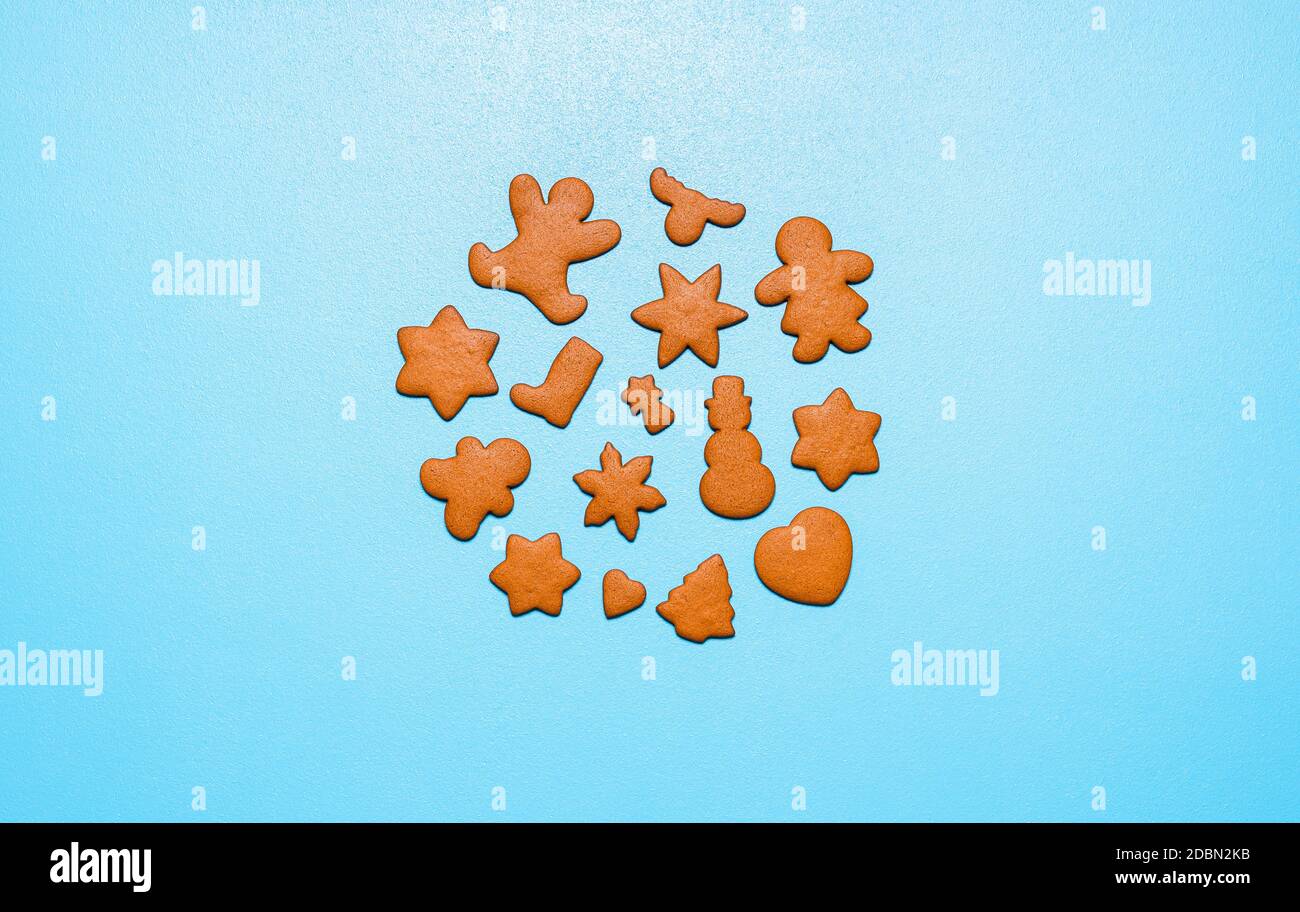 Biscuits maison de pain d'épice dans une variété de formes, isolés sur fond bleu. Plat avec biscuits de Noël en forme de cercle. Banque D'Images