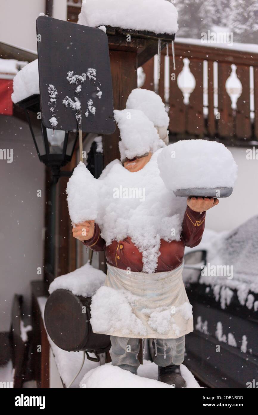 Statue en bois recouverte de neige fraîche devant un restaurant, Val Gardena, Dolomites, Italie Banque D'Images