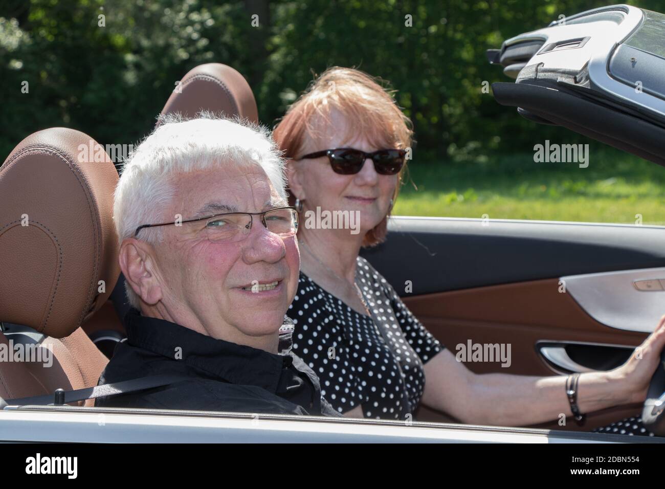 Heureux couple plus âgé avec une voiture décapotable de luxe sur une journée ensoleillée Banque D'Images