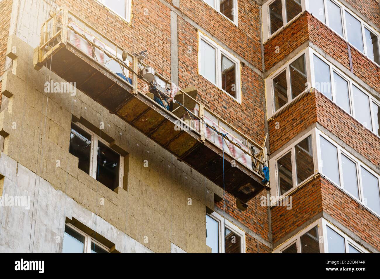 Travail à haute altitude sur les murs extérieurs de l'isolation en laine de verre et de plâtre Banque D'Images