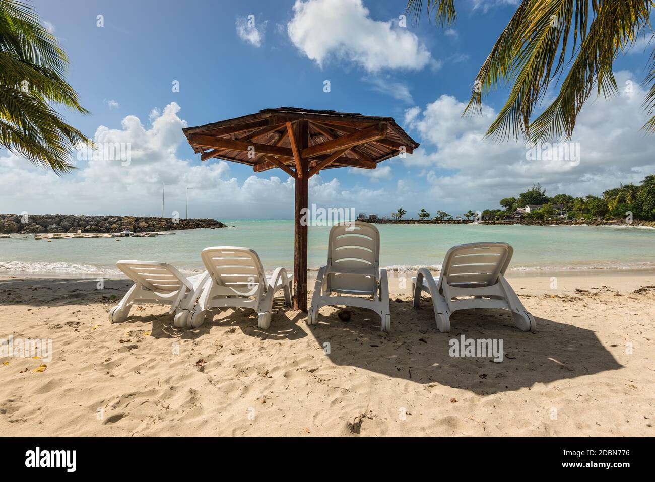 Vacances - Quatre chaises en bois et toit Palapa Beach tropical beach - l'île des Caraïbes de Guadeloupe Banque D'Images
