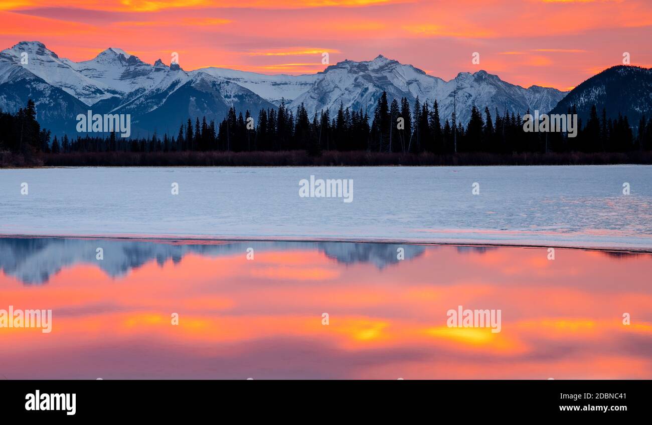 Le soleil se lève et brille de couleur au-dessus d'un lac Vermillion couvert de glace dans le parc national Banff. Banque D'Images