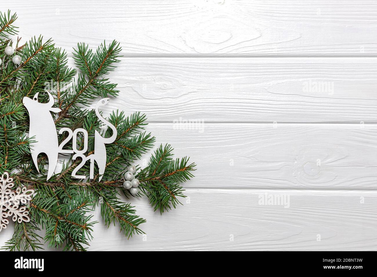 Branches de pin, déco de boeuf et flocon de neige sur fond de bois blanc. 2021. Espace de copie Banque D'Images