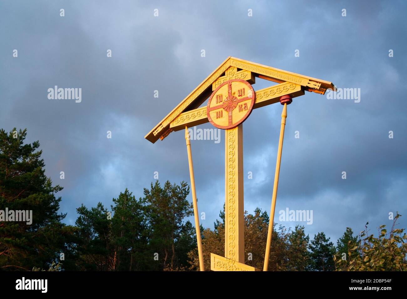 Croix orthodoxe chrétienne jaune en bois près des arbres. Symbole religieux. Banque D'Images