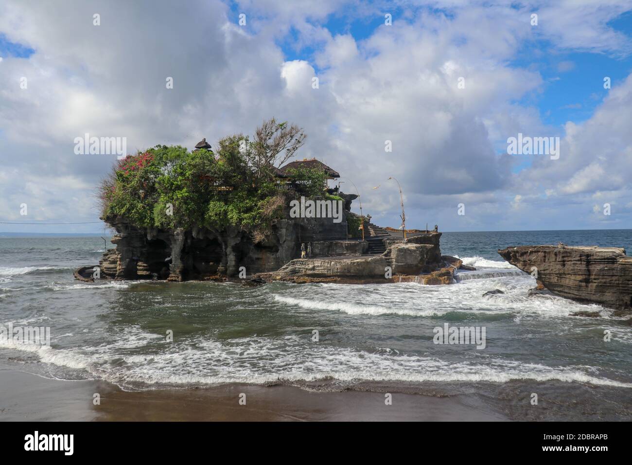 Des vagues se brisent sur une falaise au sommet de laquelle se trouve le temple hindou de Tanah Lot. Temple construit sur un rocher dans la mer au large de la côte de l'île de Bali, Indones Banque D'Images