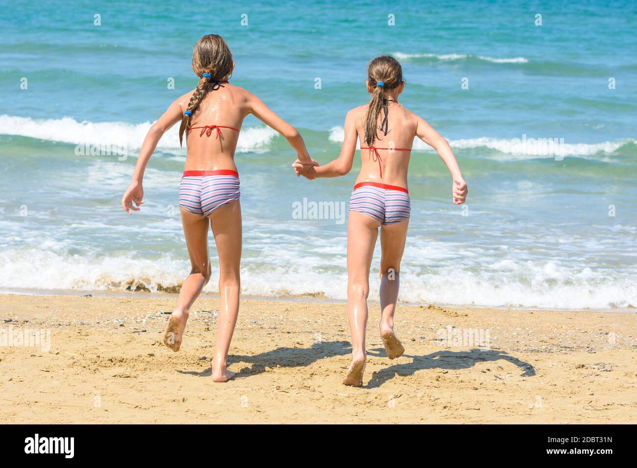 Deux petites sœurs qui s'exécutent pour nager dans la mer, visas de retour Banque D'Images