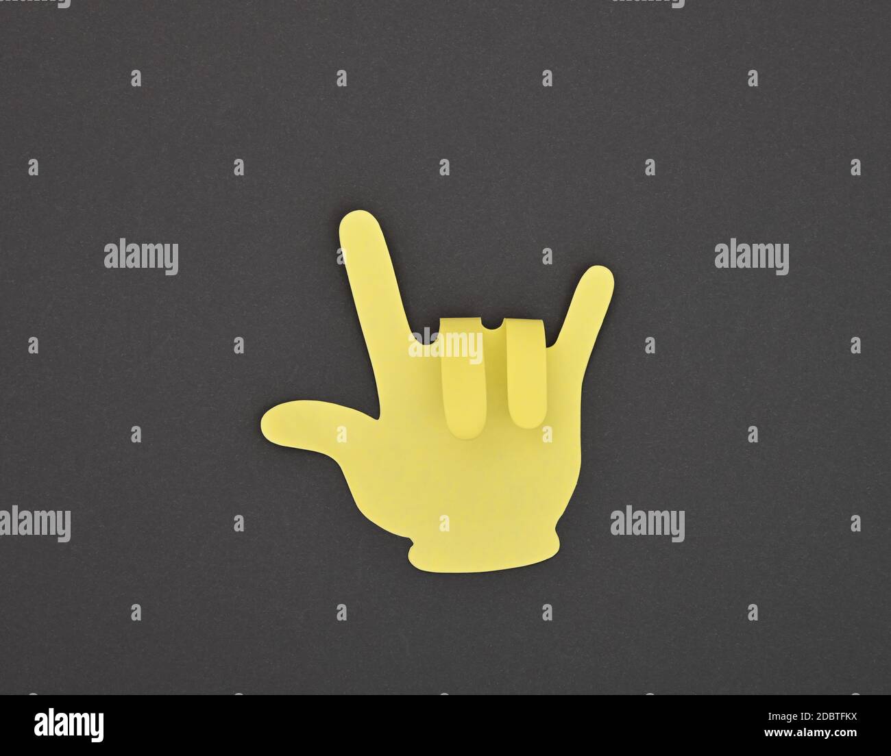 Papier fait main cornes diable jaune autocollant sur fond gris des gestes Banque D'Images