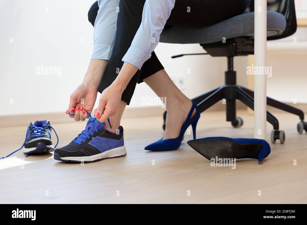 Femme changeant de talons hauts, chaussures de bureau après la journée de  travail assis sur la chaise, prête à marcher ou courir Photo Stock - Alamy
