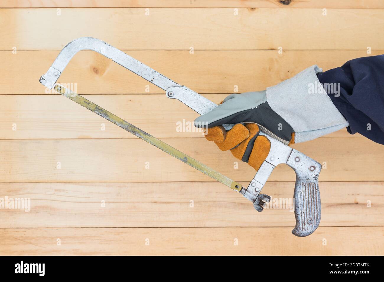 Travaillant main dans la main maintenant scie à métaux avec mur de fond en bois Banque D'Images