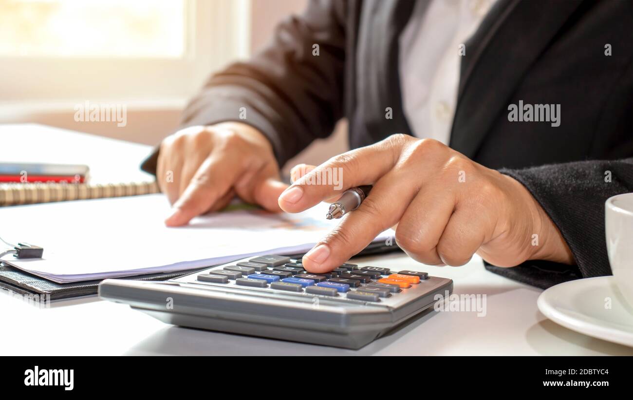 Gros plan d'hommes d'affaires ou de comptables tenant un stylo et appuyant sur la calculatrice pour calculer des informations d'affaires, des documents comptables, des affaires Banque D'Images
