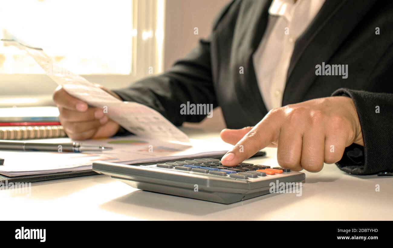 Gros plan d'hommes d'affaires ou de comptables tenant un stylo et appuyant sur la calculatrice pour calculer des informations d'affaires, des documents comptables, des affaires Banque D'Images