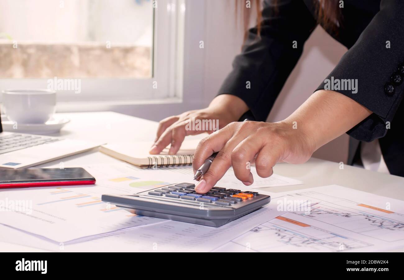 Gros plan des femmes utilisant des calculatrices pour créer des rapports comptables par fenêtre dans leurs propres maisons, concepts de calcul des coûts et concept de travail à domicile Banque D'Images