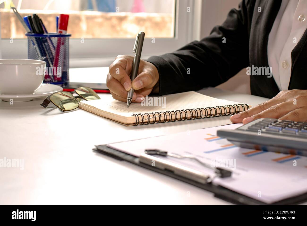 Les professionnels utilisent un stylo pour prendre des notes, y compris des calculatrices et des rapports financiers sur le bureau. Banque D'Images