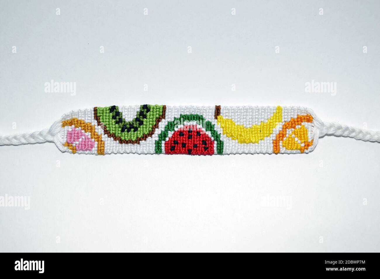 Bracelet d'amitié unique de designer blanc fait à la main de fils avec des fruits motif isolé sur fond blanc Banque D'Images