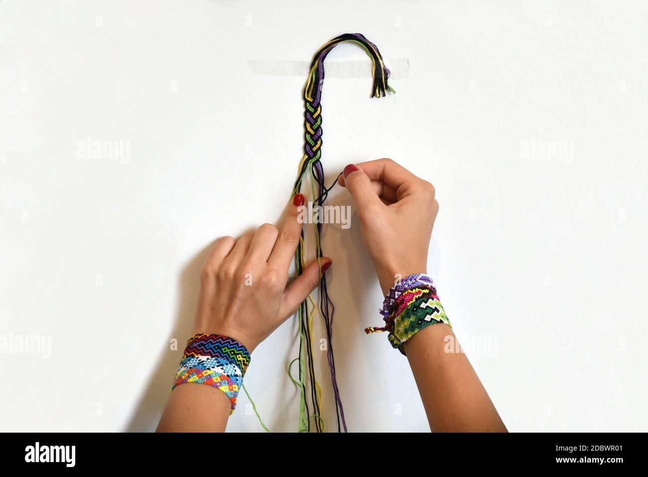 Processus de tissage du nœud pour bricoler d'amitié de bricolage. Mains de  femmes avec beaucoup de bracelets faits main sur les poignets. Étape par  étape. Arrière-plan blanc Photo Stock - Alamy