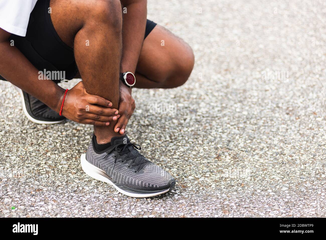 Gros plan asiatique jeune coureur sport noir homme porter montre mains joint tenir la douleur de jambe en raison de la cheville tordue cassé pendant la course à l'extérieur de la rue h Banque D'Images